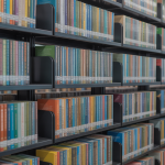 A well lit, modern library with neatly arranged shelves filled with colorful books